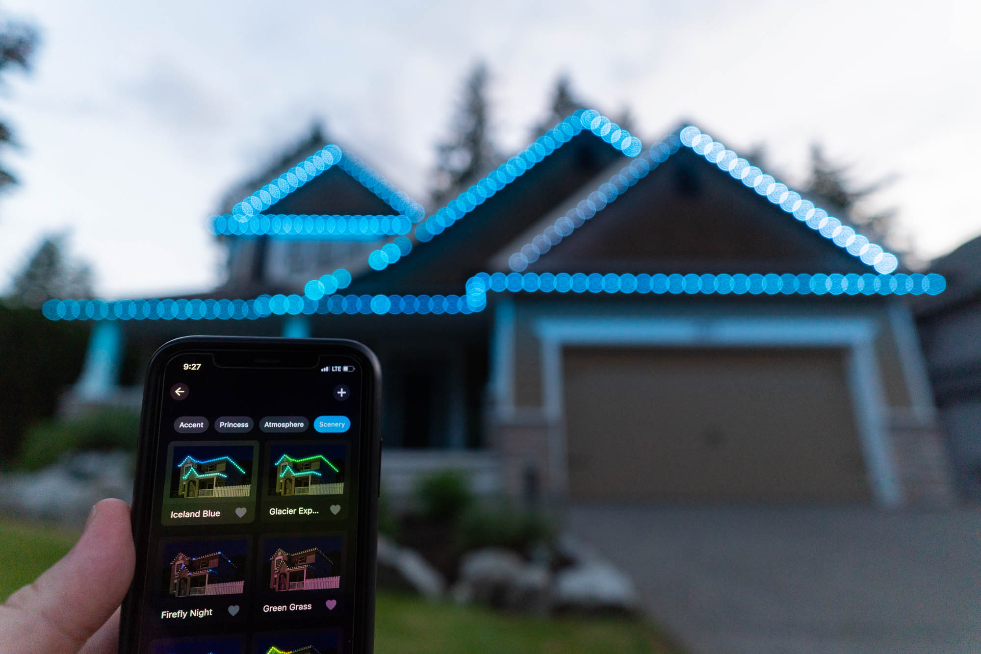 Smartphone app controlling permanent Christmas lights on a home lit in ice blue